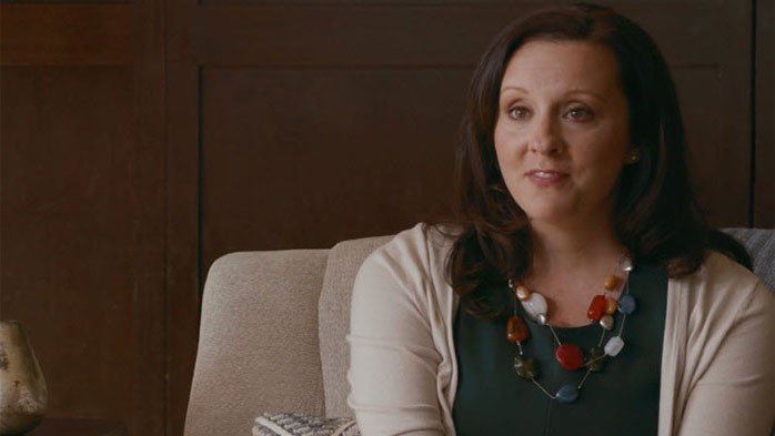 screenshot of woman sitting in a chair talking to camera